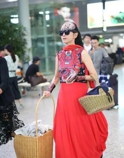 机场|60多岁的杨丽萍活出了自信,穿红色民族裙走机场,推竹筐好洋气