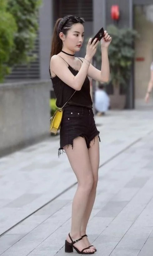 街拍:美女穿黑色背心配白色短裤,冷酷的表情吸睛无数