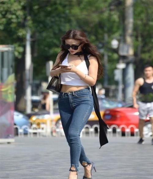 美女|街拍小姐姐一件粉色紧身T恤，搭配蓝色长牛仔裤