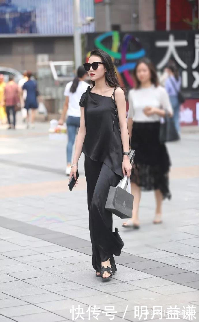 美女脚上踩着一双黑色的高跟凉鞋，让她出街的时候带着优雅的姿态