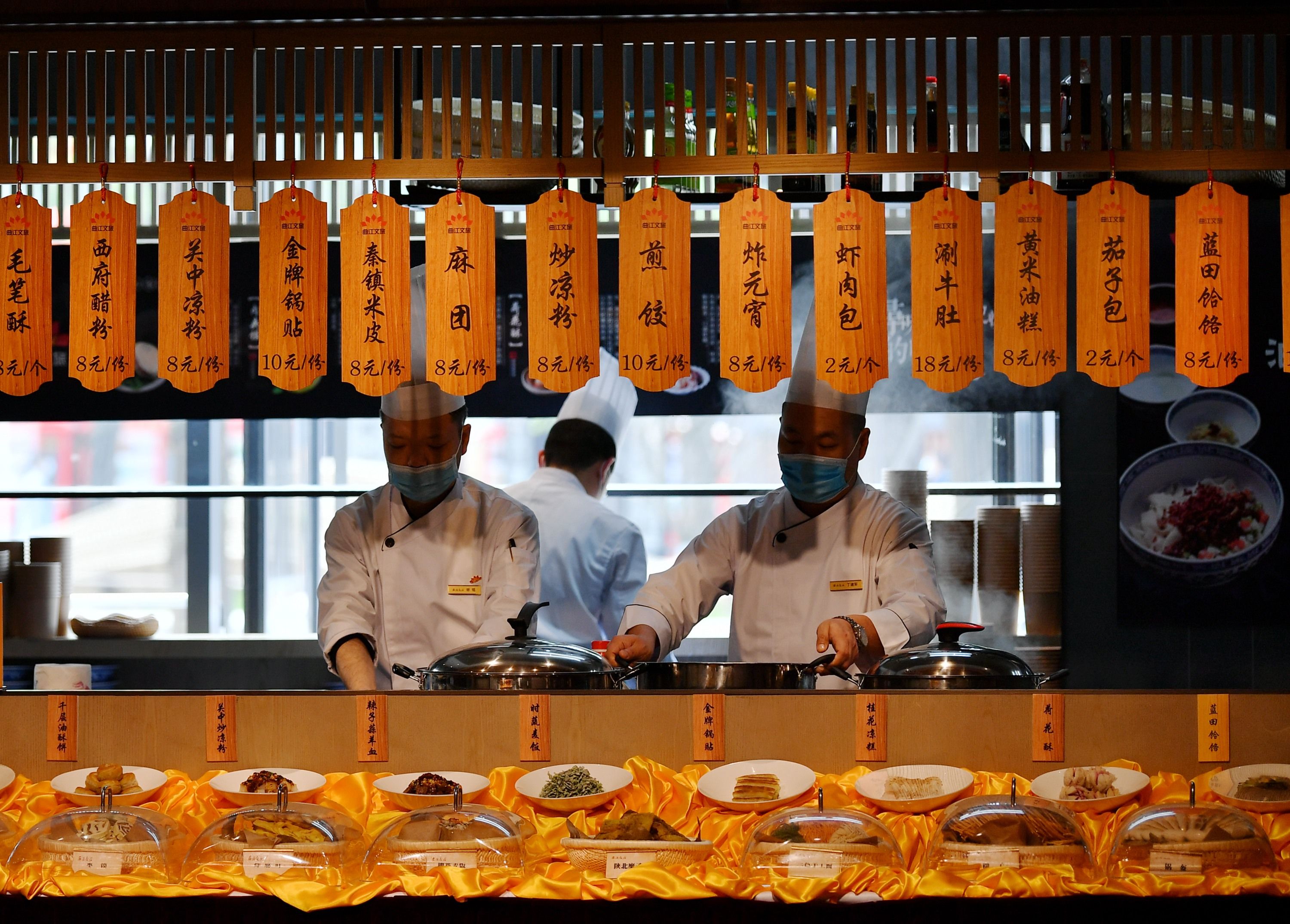 "    4月23日,在西安大唐不夜城步行街一家餐厅,厨师正在烹饪食品