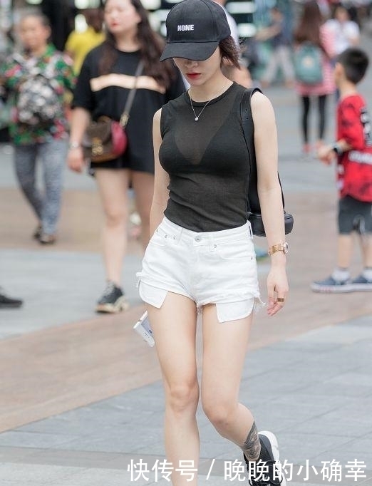 路人街拍，小姐姐下身穿的是一件白色的牛仔短裤，展示白皙的双腿