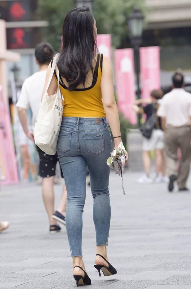 时尚街拍：蓝色紧身牛仔裤搭配黄色无袖背心，小姐姐很有活力