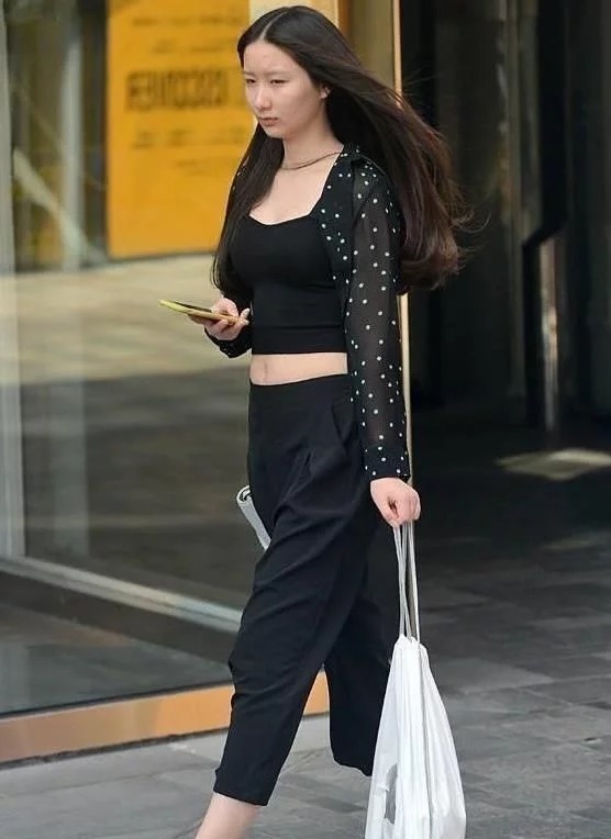 街拍:小姐姐身穿红色无袖上衣,白色的长裤,造型很时尚