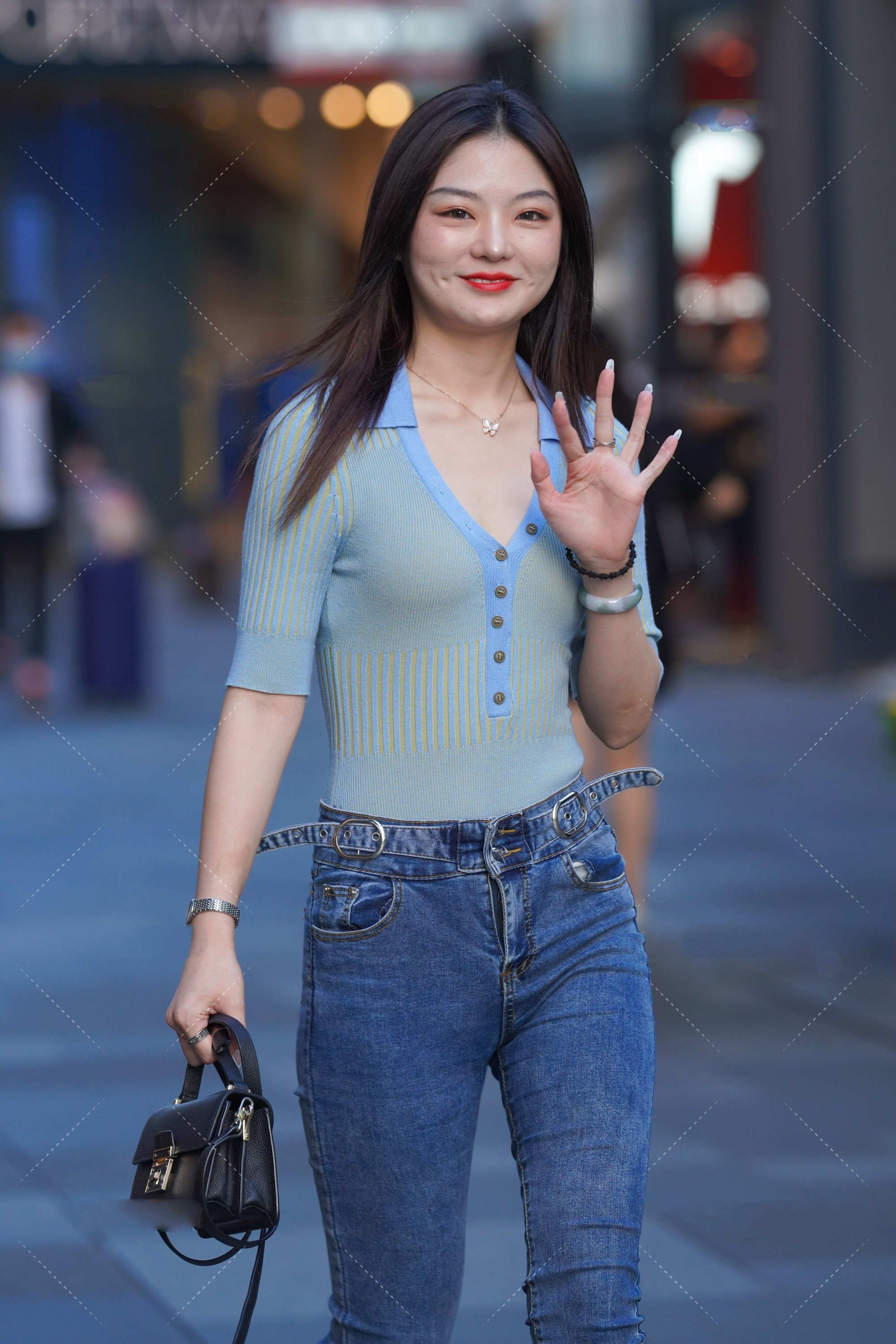 蓝绿色修身上衣搭配深色牛仔裤，手拿黑色手提包，清爽简约的搭配