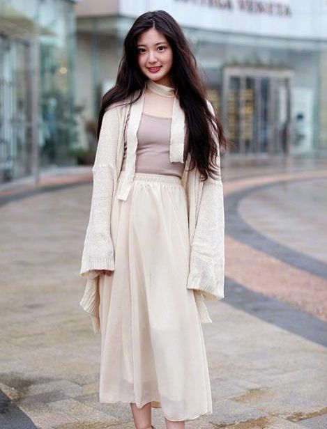 穿着白色|街拍：小姐姐穿着白色的吊带背心搭配牛仔长裤，气质甜美性感