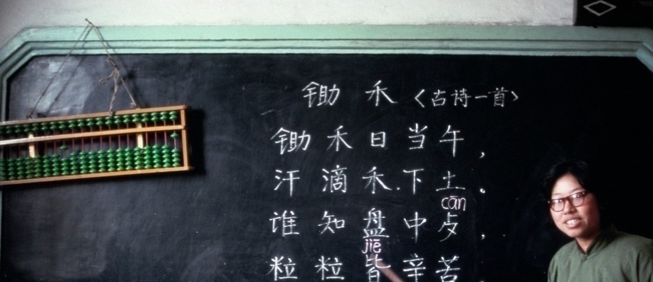 那个年代$70年代罕见的老照片:胸前佩戴大红花是荣耀的象征,老师在课堂教授古诗