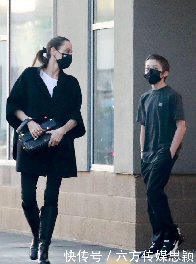 安吉丽娜·朱莉穿黑色斗篷上衣搭配细腿裤,和儿子逛街,真潇洒