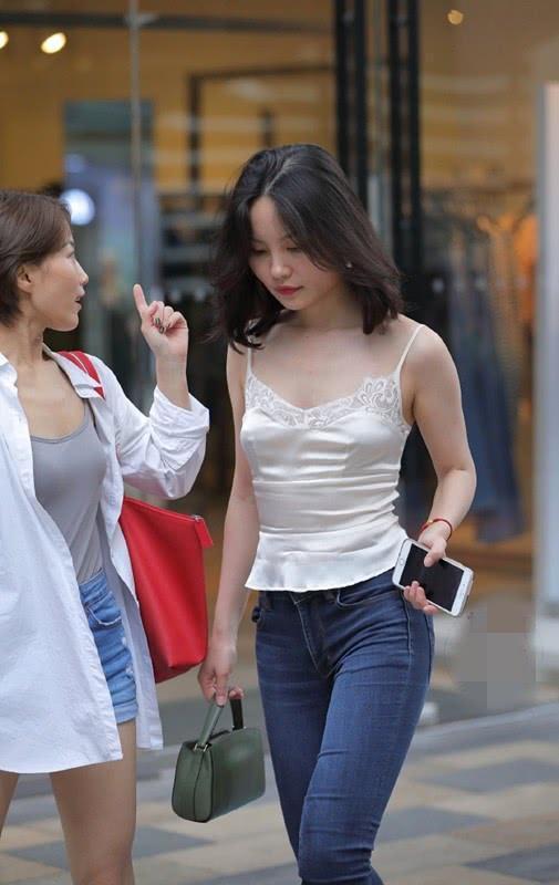 街拍时尚大气的美女,简洁的吊带背心搭配牛仔裤,显得十分修身立体