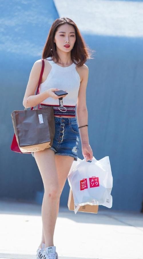 身穿|街拍小姐姐身穿喇叭一字肩上衣搭配浅蓝色牛仔热裤,美丽动人
