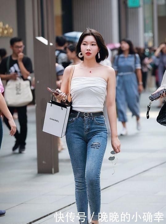 路人街拍，小姐姐下身穿的是一件白色的牛仔短裤，展示白皙的双腿
