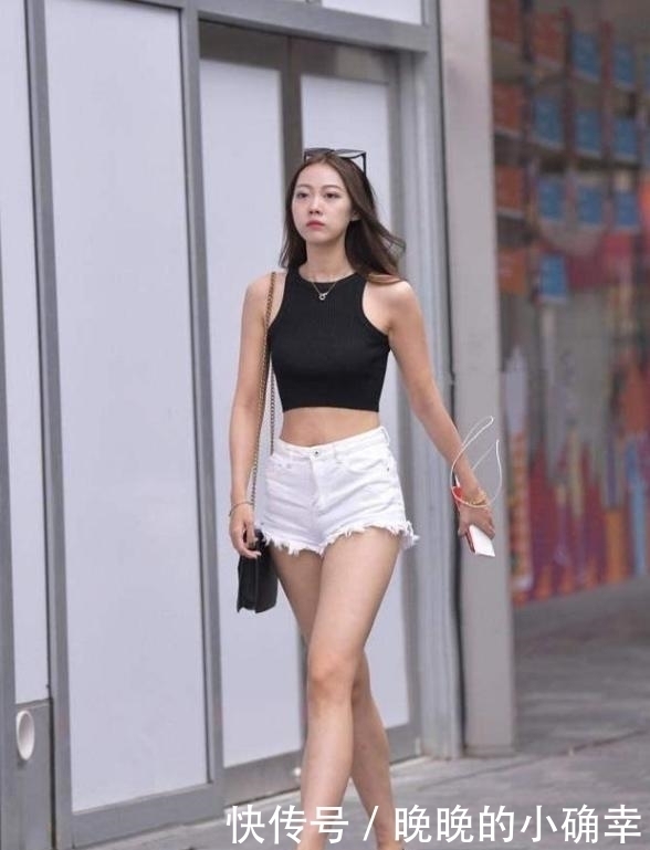 路人街拍,小姐姐下身穿的是一件白色的牛仔短裤,展示白皙的双腿