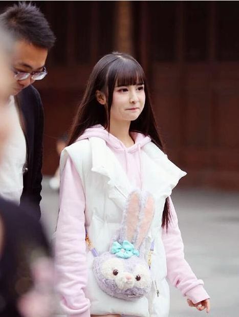 穿着白色|街拍：小姐姐穿着白色的吊带背心搭配牛仔长裤，气质甜美性感