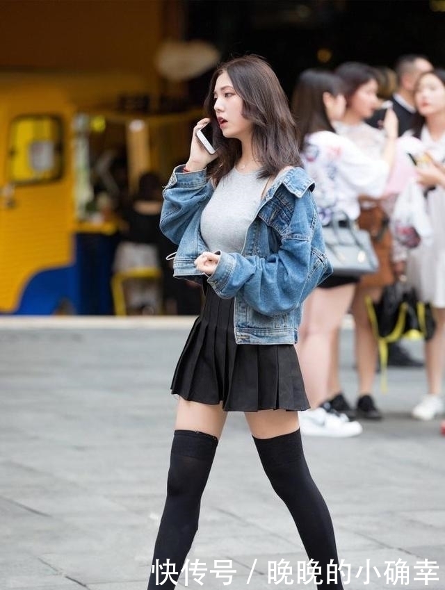 路人街拍,小姐姐下身穿的是一件白色的牛仔短裤,展示白皙的双腿