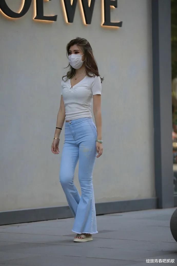 白色V领修身T恤，加上喇叭牛仔裤，尽显出休闲时尚的风格