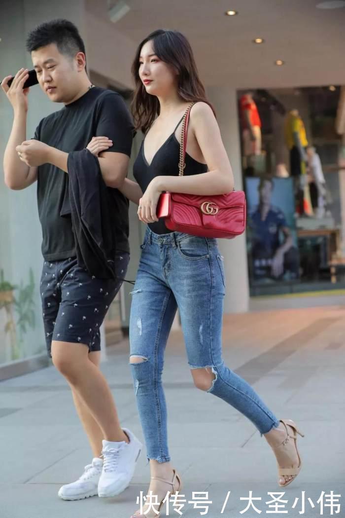 美女街拍小姐姐黑色的吊带抹胸背心搭配浅色的牛仔长裤,性感丰满身材尽显