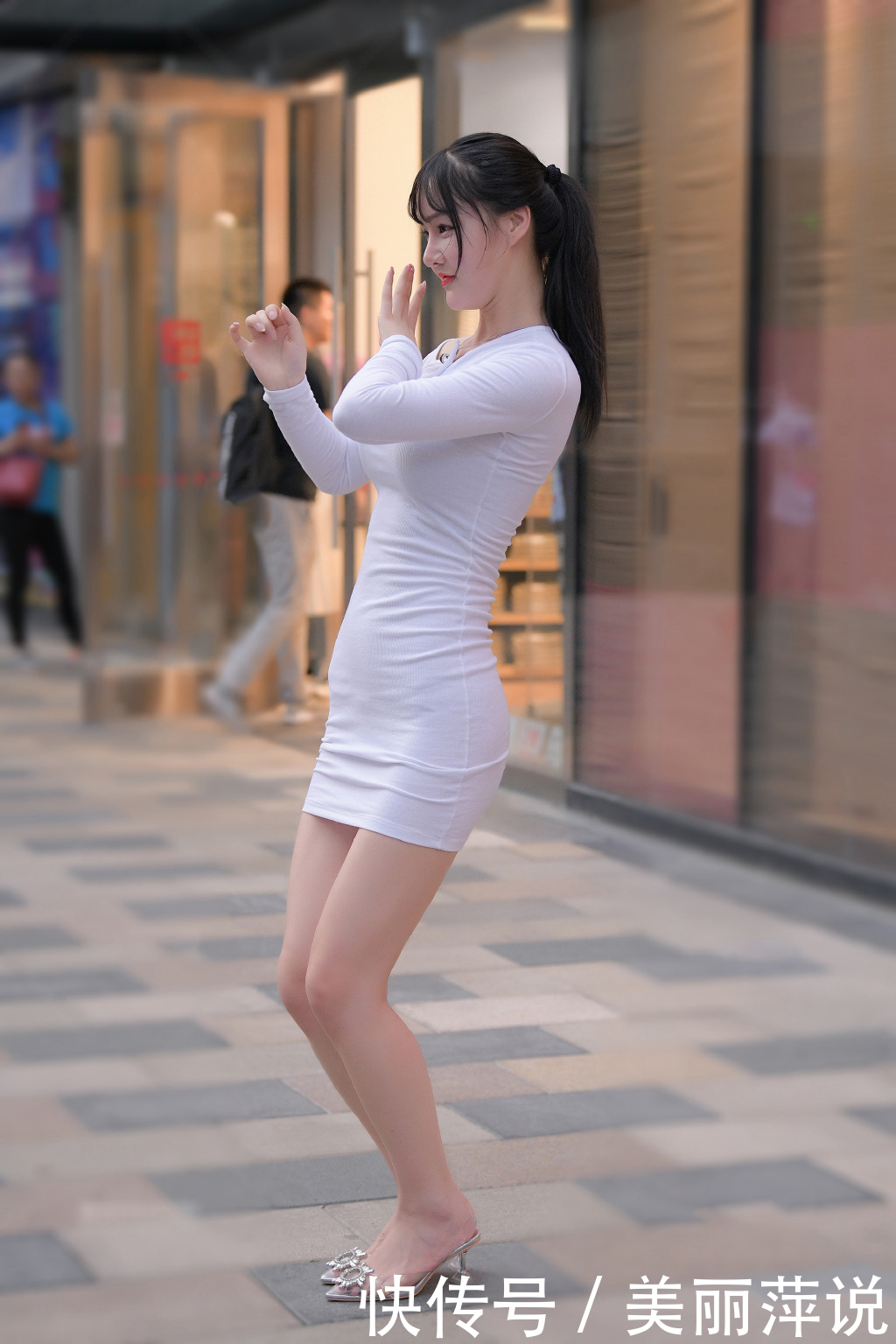 美女街拍小姐姐身穿白色修身连衣裙，在街头载歌载舞，妩媚动人